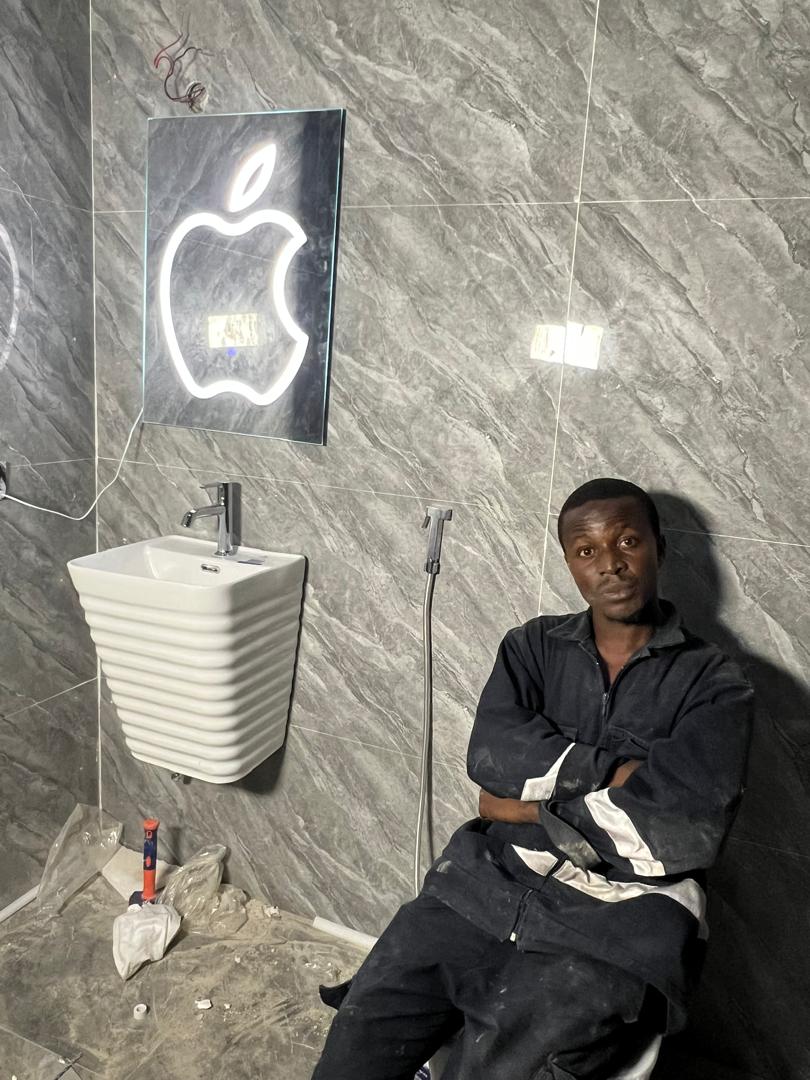 A DYP technician completing basin fixture work in a tiled bathroom.