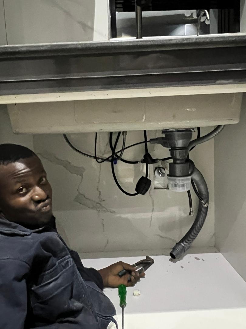 DYP technician inspecting exposed pipework beneath a basin